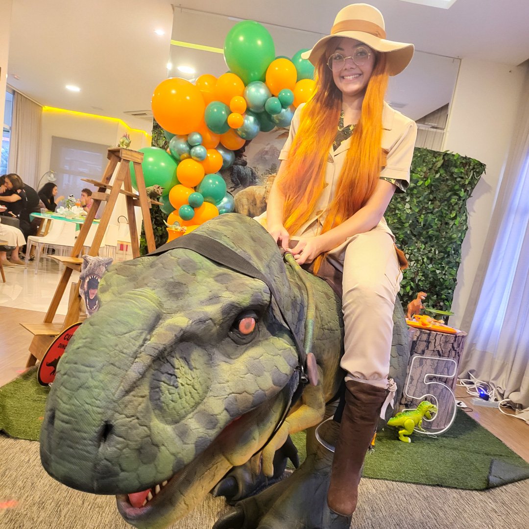 Crianças interagindo com dinossauro baby hiper-realista em evento na região de Valinhos
