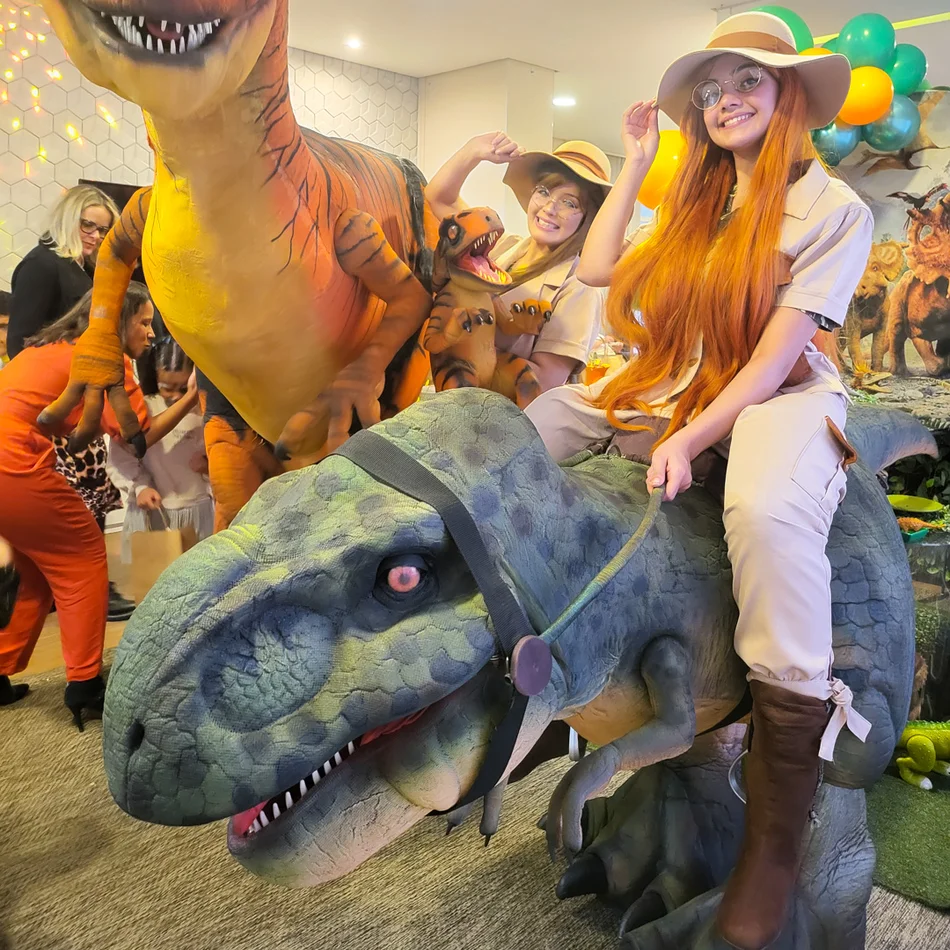 Crianças interagindo com dinossauro baby em salão de festas em Mauá