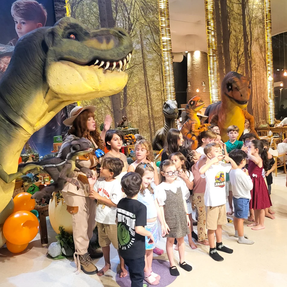 Equipe de exploradores e dinossauros baby em show interativo para festa de um ano